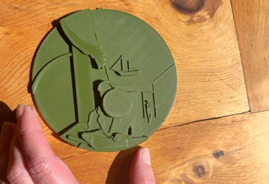 Ein rundes flaches Handtellergroßes grünes Reliefmodell über das Kunstwerk Einsiedler