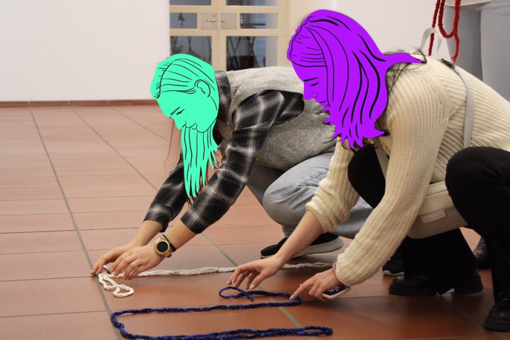 kaksi nuorta naista koskettelevat lattialla olevia naruja